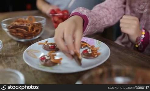 Many different human hands taking christmas homemade cookies from the plate. Hands of three generation family taking tasty reindeer cookies until the plate is empty. Child&acute;s hand on empty plate over rustic wooden table background. Dolly shot.