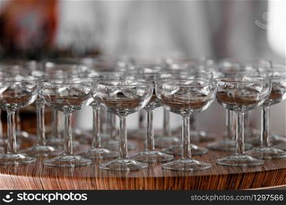 Many elegant empty glasses of wine or champagne on the wooden table in wedding day. Set of blank empty glasses displayed in rows. Preparation for the holiday.. Many elegant empty glasses of wine or champagne on the wooden table in wedding day. Set of blank empty glasses displayed in rows. Preparation for the holiday
