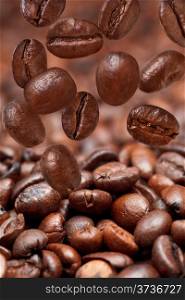 many falling beans and dark roasted coffee beans background with focus foreground