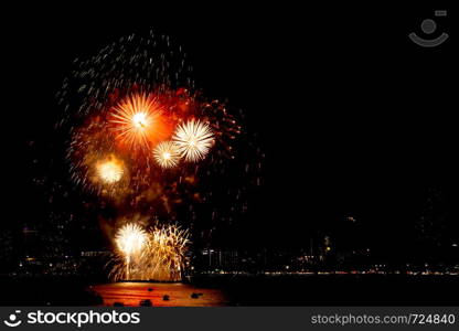 Many flashing fireworks with night cityscape background celebrate New Year.