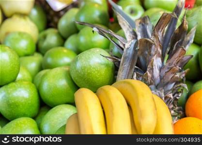 Many fresh bananas,apples and pineapples are sale on a stall at grocery food store. Many fresh bananas,apples and pineapples are sale