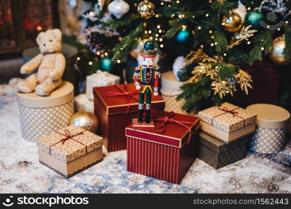 Many gifts under decorated New Year tree. Home interior and festive atmosphere. Winter holidays concept. Horizontal picture with many wrapped gifts. Calm atmosphere and festive event.