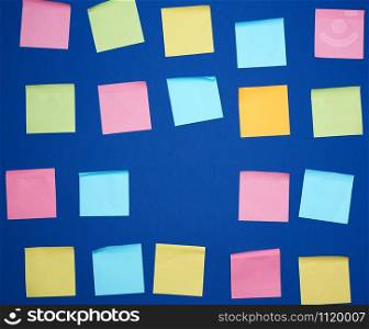 many glued square multi-colored blank stickers on a blue background, close up