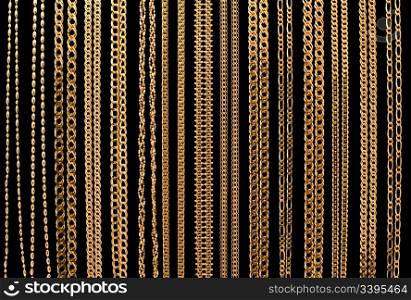 many gold chain necklaces over black background