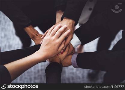 Many happy business people stacking hands together with joy and success. Company employee celebrate after finishing successful work project. Corporate partnership and achievement concept.