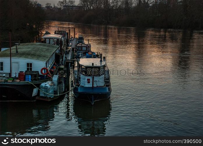 many House boats are beached on the side of the River Thames at sunset