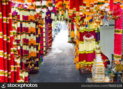 Many indian garlands of colorful flowers for temple and ceremony decoration hanging at asian street market