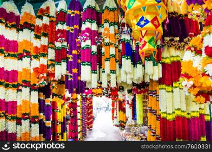 Many indian garlands of colorful flowers for temple and ceremony decoration hanging at asian street market