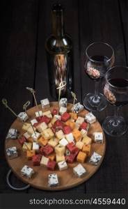 many kinds of cheeses on wooden end of a tree with reed wine
