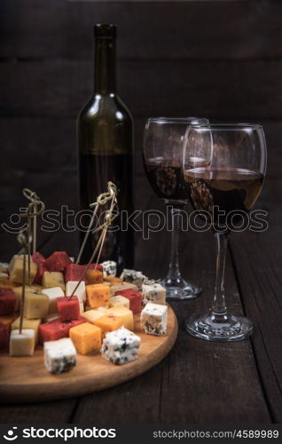 many kinds of cheeses on wooden end of a tree with reed wine