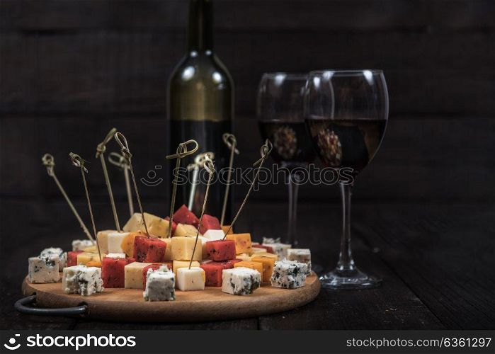 many kinds of cheeses on wooden end of a tree with reed wine