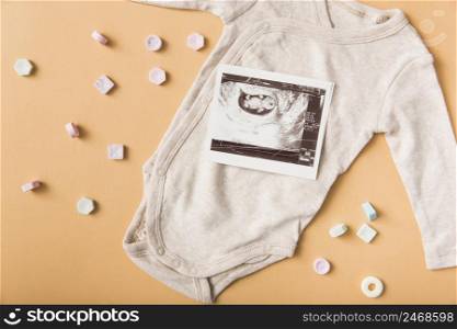 many mint candies with sonography picture baby onesie orange backdrop