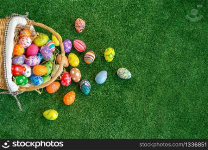 Many mixed colorful easter eggs on basket and on green grass fields with free space. Holiday background.