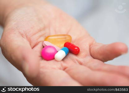 Many multi-colored pills in a Senior's hands. Painful old age. Caring for the health of the elderly nurse. Many multi-colored pills in a Senior's hands. Painful old age. Caring for the health of the elderly