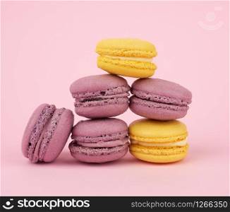many multi-colored round baked macarons cakes on a light pink background, close up