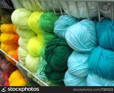 Many multicolored balls of wool yarn in metal mesh trays.