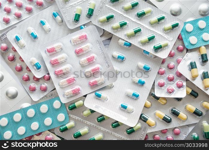 Many multicolored pills in silver blister packs. Pharmaceutical preparations, located in the form of a background. Top view, flat lay. Multicolored pills as background
