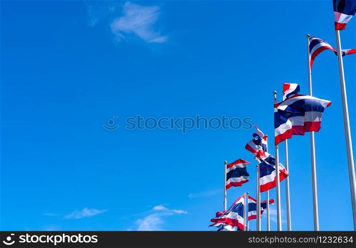 Many of Thailand flag waving on top of flagpole against blue sky. Thai flag was drawn to top of the flagpole. Red, blue, and white color rectangle fabric. National flag of the Kingdom of Thailand.