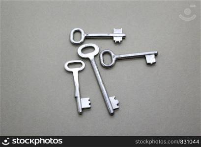 Many old vintage keys on a beige paper background