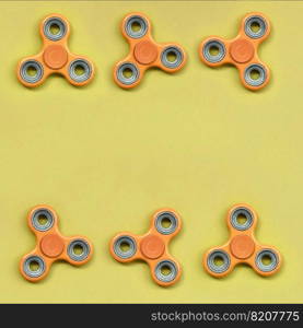 Many orange fidget spinners lies on texture background of fashion pastel orange color paper in minimal concept.. Many orange fidget spinners lies on texture background of fashion pastel orange color paper
