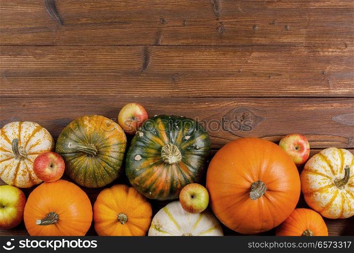 Many orange pumpkins and apples on wooden background, Halloween concept. Pumpkins on wooden background