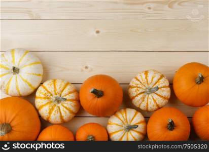 Many orange pumpkins on light wooden background, Halloween concept, top view with copy space. Pumpkins on wooden background