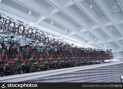 Many parked bikes on a train station, rack