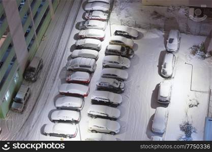 Many parking cars in snow on night winter parking lots. aerial view on parking