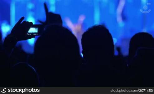Many people stand back near the stage in blue on the concert and takes photos
