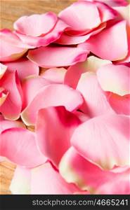 Many pink petals on wooden background for wallpaper