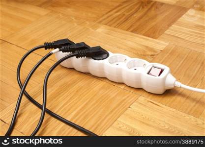 Many plugs plugged into electric power bar on floor
