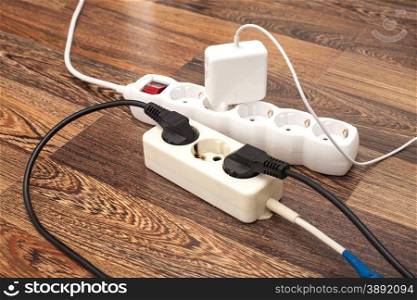 Many plugs plugged into electric power bars on floor