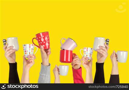many raised hands up with ceramic cups on a yellow background, recruitment concept, join our team