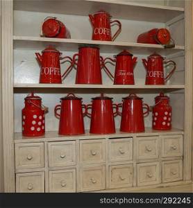 Many Red Coffee Makers and Red Metal Tea Containers on a Shelf.. Many Red Coffee Makers and Red Metal Tea Containers on a Shelf