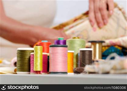 Many reels of colored threads, seamstress at the bottom