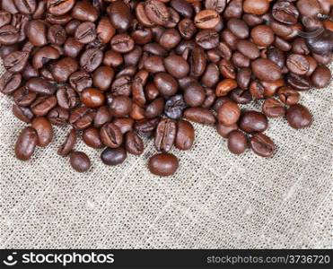 many roasted coffee beans on cloth close up