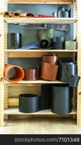 Many rolls leather on shelf in leather workshop.