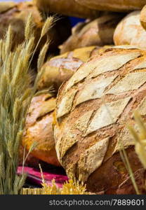 many rustic baked traditional rye bread loaves on a market stall outdoor