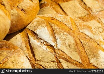 many rustic baked traditional rye bread loaves on a market stall outdoor. Food background
