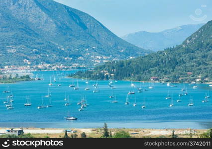 Many sailing vessels in bay. Hazy summer Lefkada coast landscape (Nydri, Greece, Ionian Sea).