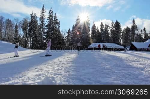 many skiers rides on slopes of mountain peaks in evening, before sunset