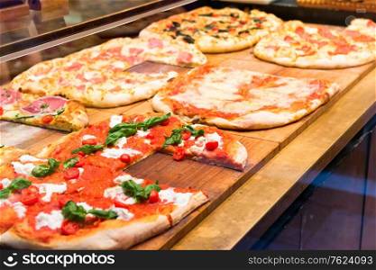 Many slices of pizza on wooden table in restaurant
