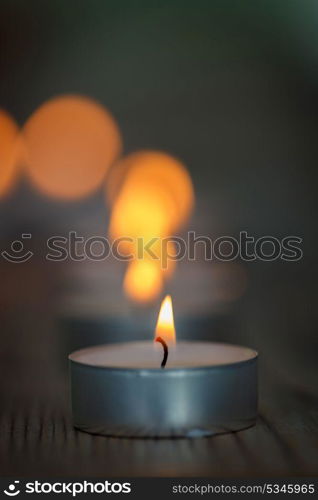 Many small burning candles on a wooden surface