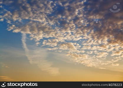 many small clouds in dark yellow and blue sunset sky in early morning