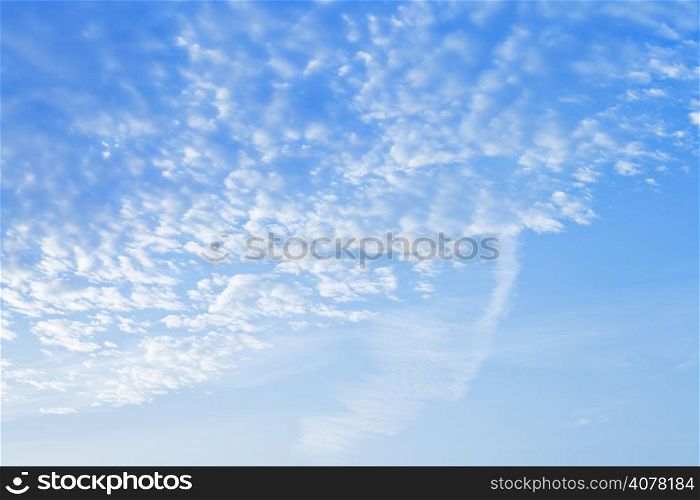 many small puffy white clouds in blue sunrise sky in early morning