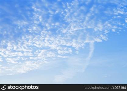 many small puffy white clouds in blue sunrise sky in early morning