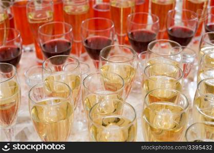 many stemwares with champagne, red wine and fruit drinks on buffet table, shallow DOF