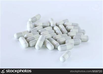 Many tablets, pills piled on a white background.