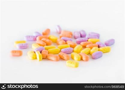 Many tablets, pills piled on a white background.