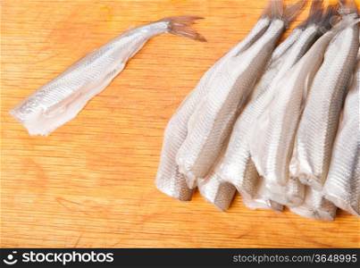 many uncooked trunk small fish on wood board